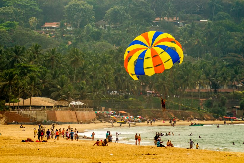 parachuter gliding over a populated beach